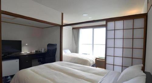 a hotel room with two beds and a television at Hamakan Hotel in Unzen