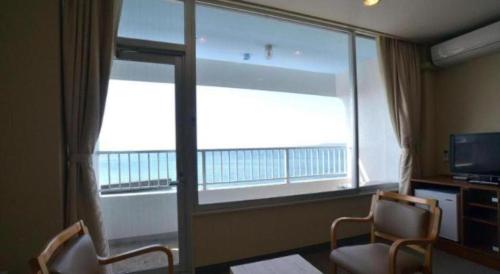 a room with two chairs and a large window at Hamakan Hotel in Unzen