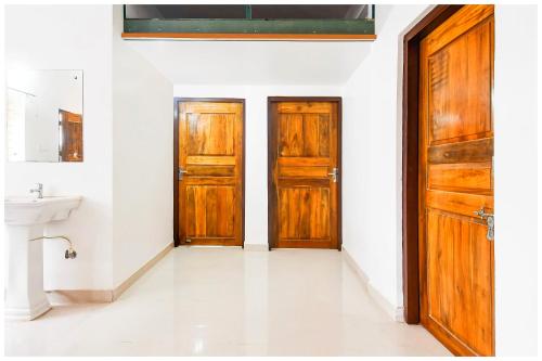 two wooden doors in a white room with a sink at Hotel Shree Laxmi Resorts - Patia Railway Station- Fully Air Conditioning Hotel - Luxury & Spacious Room -A Premium Hotel in Cuttack