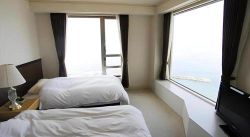 a hotel room with two beds and a window at Hotel AreaOne Banjinmisaki in Kashiwazaki