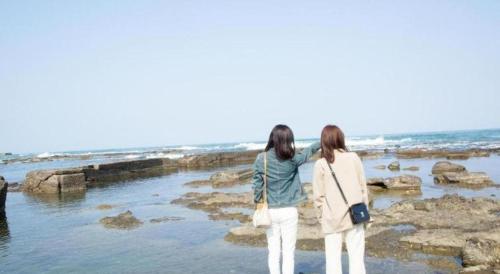 two women standing on the rocks near the ocean at Hotel AreaOne Banjinmisaki in Kashiwazaki