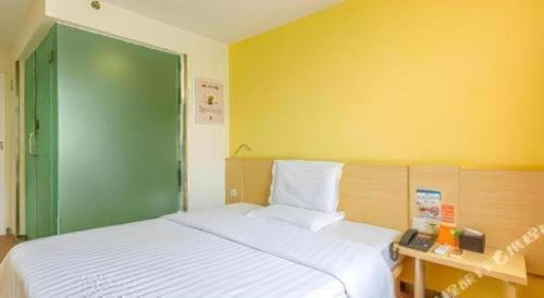 a bedroom with a large white bed with a green door at 7 Days Inn West Gate of Taiyuan University of Technology in Taiyuan