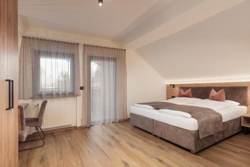 a bedroom with a bed and a desk and a window at Aparthotel Familiaris - Family Apartments - Pools & Spa in Dolomites in Valdaora