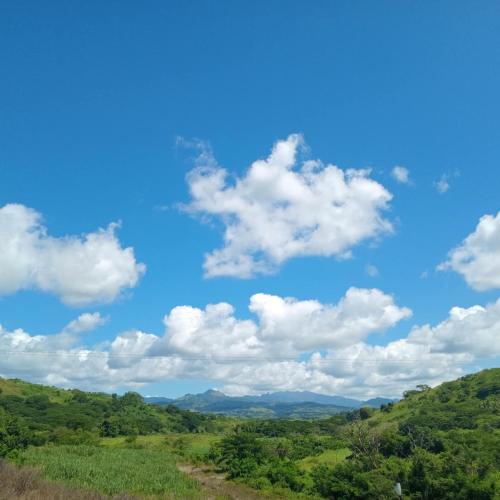a blue sky with white clouds over green hills at theoutbackhotel in Tonge