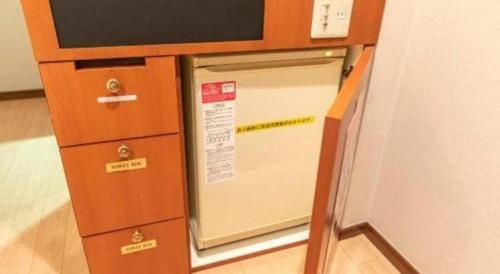 a small kitchen with a microwave in a cabinet at Tabist Hotel Please Kobe in Kobe