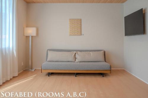 a couch in a living room with a lamp at Ginkgo House ギンコハウス in Fujiyoshida