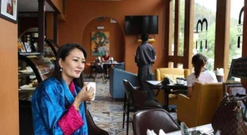 a woman sitting in a restaurant holding a cup of coffee at The Pema by Realm in Thimphu