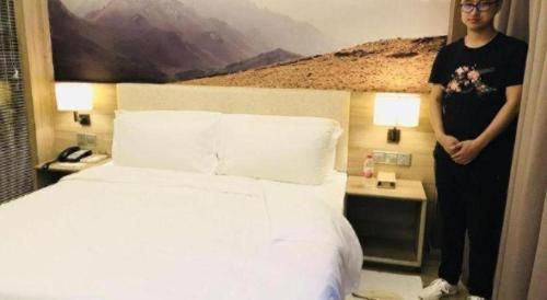 a man standing next to a bed in a hotel room at Atour Hotel Xi'an High Tech Dazhai Road in Xi'an