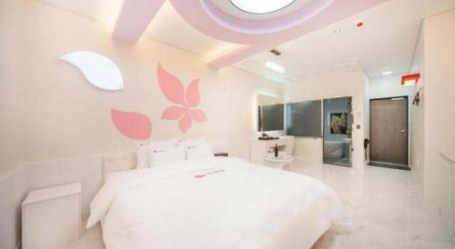 a white bedroom with a large bed with pink flowers on the wall at SH Hotel in Mokpo