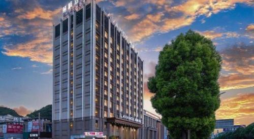 a tall building with a tree in front of it at Lavande Hotels· Guizhou Anshun Xi Railway Station in Anshun
