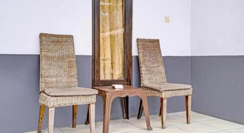 two chairs and a table in front of a mirror at OYO 90405 Penginapan Sasti Kuningan in Kuningan