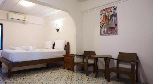 a bedroom with a bed and a table and chairs at Nan Lanna Hotel in Nan