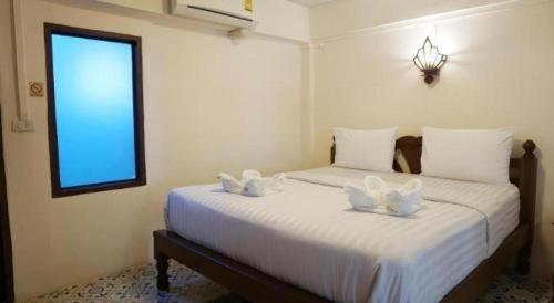a bedroom with two beds with white sheets and a window at Nan Lanna Hotel in Nan