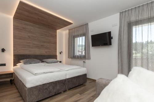 a bedroom with two beds and a flat screen tv at Aparthotel Familiaris - Family Apartments - Pools & Spa in Dolomites in Valdaora