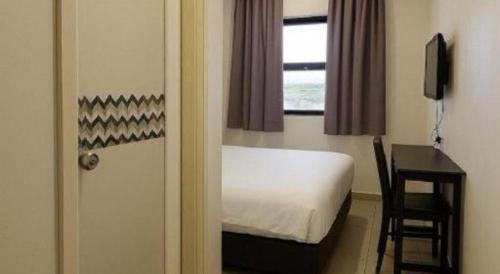 a bedroom with a bed and a desk and a window at G Six Hotel in Sitiawan