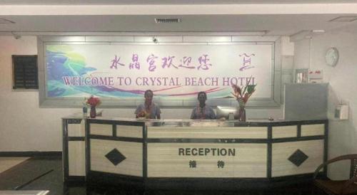 two people standing at a reception desk in a building at Crystal Palace Hotel in Port Vila