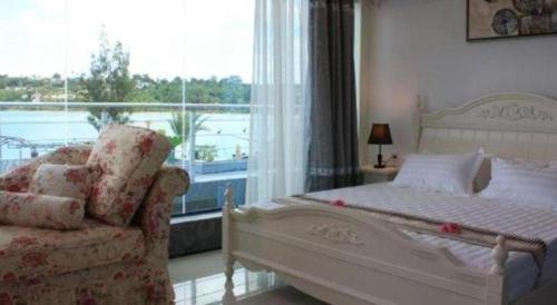 a bedroom with a bed and a chair and a window at Crystal Palace Hotel in Port Vila