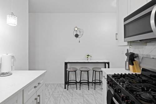a white kitchen with a stove and bar stools at NYC cozy & stylish 1 Bed Apt perfect for 4 guest in West New York