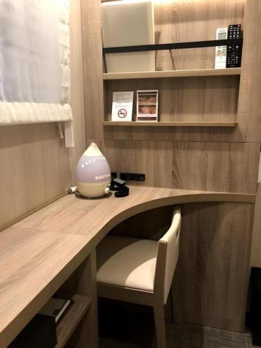 a desk with a chair and a vase on it at Hotel IL FIORE Kasai in Tokyo