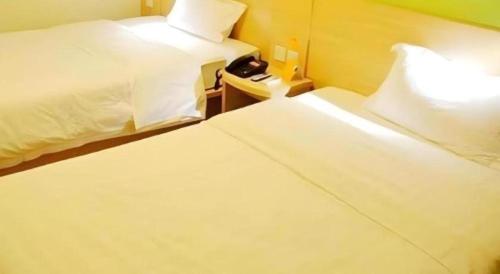 a hotel room with two beds and a telephone at 7 Days Inn Guangrao Bus Station in Dongying