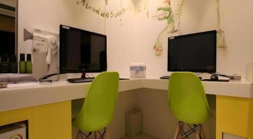 a desk with two monitors and two green chairs at Crossing Hotel in Seoul