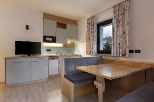 a kitchen with a table and a television in a room at Aparthotel Familiaris - Family Apartments - Pools & Spa in Dolomites in Valdaora