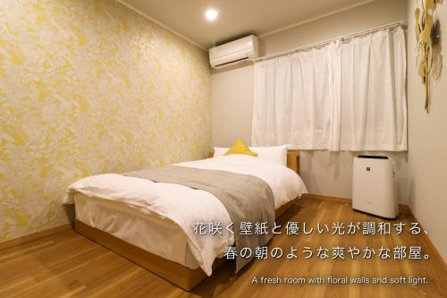 a bedroom with a bed and a window at 金鱗湖まで徒歩2分 湯布院 天然温泉ヴィラ 響 -hibiki- in Yufu