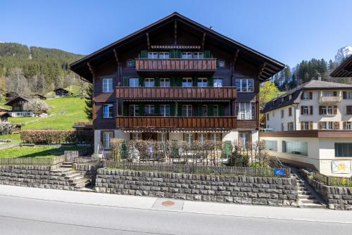 a large house with a wooden roof on a street at Zentrale Ferienwohnung in Grindelwald in Grindelwald