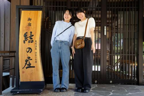 two women standing next to each other in front of a sign at Onyado Yuinosho, Shirakawago in Shirakawa