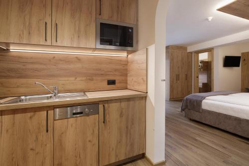 a bathroom with a sink and a bedroom with a bed at Aparthotel Familiaris - Family Apartments - Pools & Spa in Dolomites in Valdaora