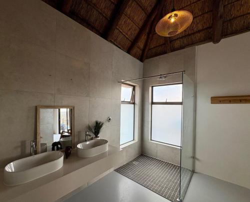Un baño con dos lavabos y una ducha de cristal. en Pezulu Lodge, en Bela-Bela