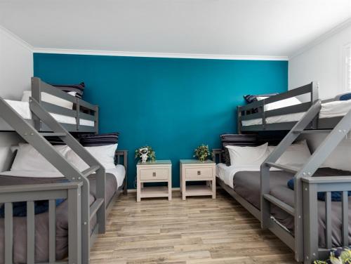 two bunk beds in a room with a blue wall at Skyes Beach House - Downstairs Accommodation in Surf Beach