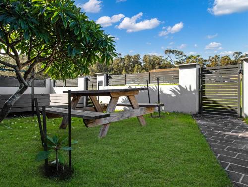 a picnic table and a tree in the grass at Skyes Beach House - Downstairs Accommodation in Surf Beach