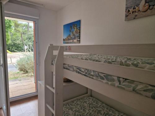 Schlafzimmer mit Etagenbett und Glasschiebetür in der Unterkunft Appartement pour 4 à 6 personnes avec piscine in Le Verdon-sur-Mer