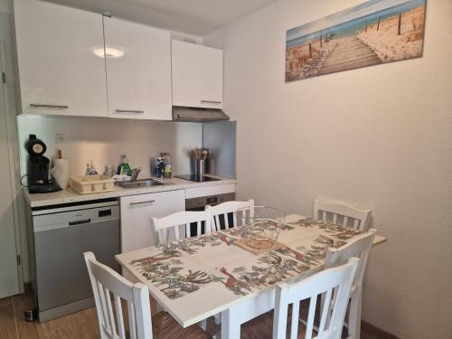 eine Küche mit einem Tisch und Stühlen in einer Küche in der Unterkunft Appartement pour 4 à 6 personnes avec piscine in Le Verdon-sur-Mer