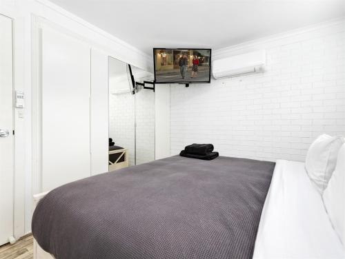 a bedroom with a bed and a tv on a wall at Skyes Beach House - Downstairs Accommodation in Surf Beach