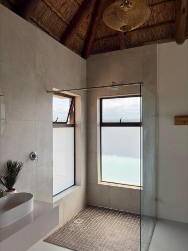 a bathroom with a shower and a sink and two windows at Pezulu Lodge in Warmbaths