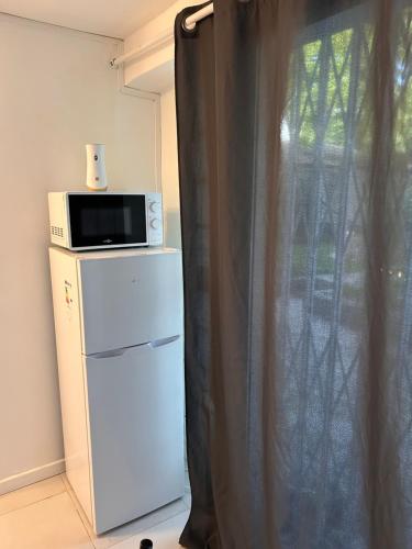 a microwave on top of a refrigerator next to a window at Two-room apartment in Villiers-le-Bel
