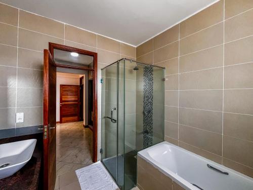 a bathroom with a shower and a tub and a sink at Eliana's nyali 3 min to the beach homes in Mombasa