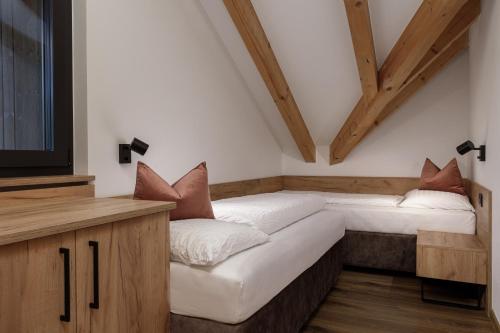 a room with two beds and a tv and wooden ceilings at Aparthotel Familiaris - Family Apartments - Pools & Spa in Dolomites in Valdaora