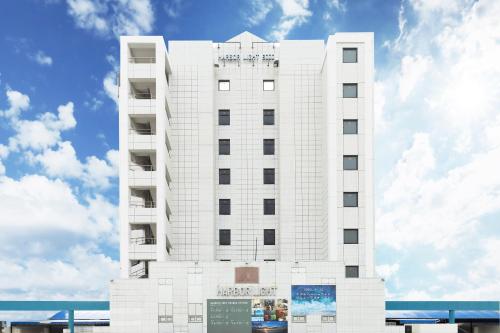 a white hotel building with a sky in the background at Moji HOTEL HARBOR LIGHT in Kitakyushu