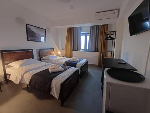 a hotel room with two beds and a flat screen tv at G Residence in Ploieşti