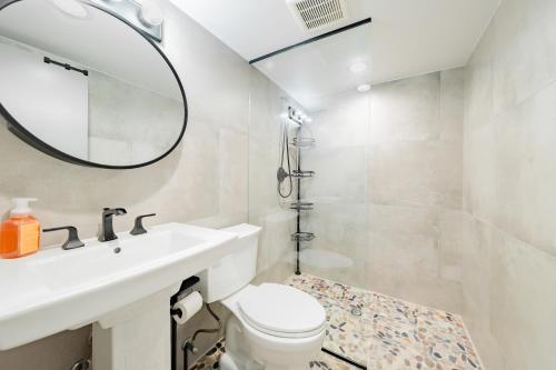 a bathroom with a sink and a toilet and a mirror at Luxury 6BR House with Pool & Outdoor BBQ in Plainview