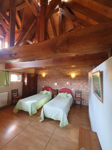 two beds in a room with wooden ceilings at Le Pigeonnier de Roudet in Larrazet