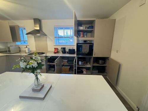a kitchen with a vase of flowers on a table at Detached 4BR House - Private Garden, Garage & Parking - Perfect for Long Stays, Families, Contractors in Canterbury
