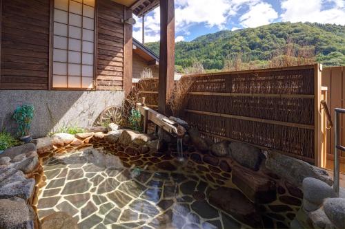 a house with a water fountain in front of a house at Onyado Yuinosho, Shirakawago in Shirakawa