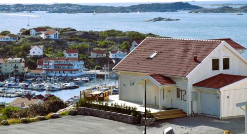 a white house with a marina with boats in the water at Panoramic view on Ellos top with 500m to sea in Ellös