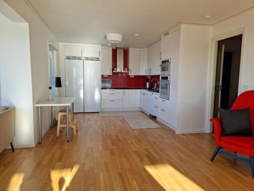 a kitchen with white cabinets and a red chair at Panoramic view on Ellos top with 500m to sea in Ellös