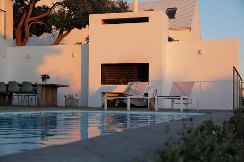 a swimming pool with a table and chairs next to a house at Blanc de Blanc in Yzerfontein