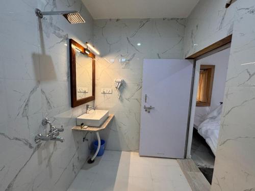 Un baño blanco con lavabo y espejo. en Homestay Jaisalmer, en Jaisalmer